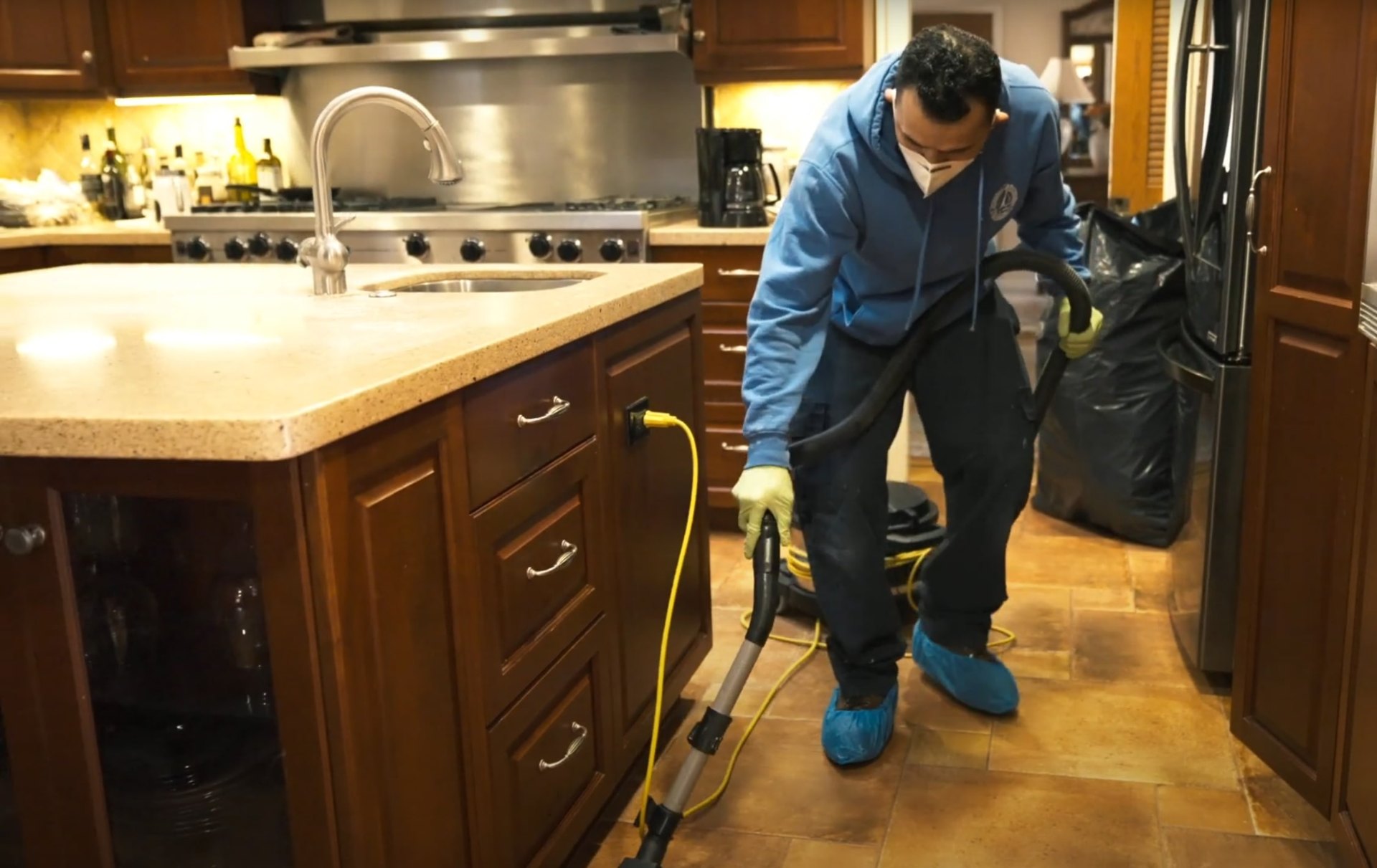 Professional water damage restoration technician using specialized equipment in residential kitchen