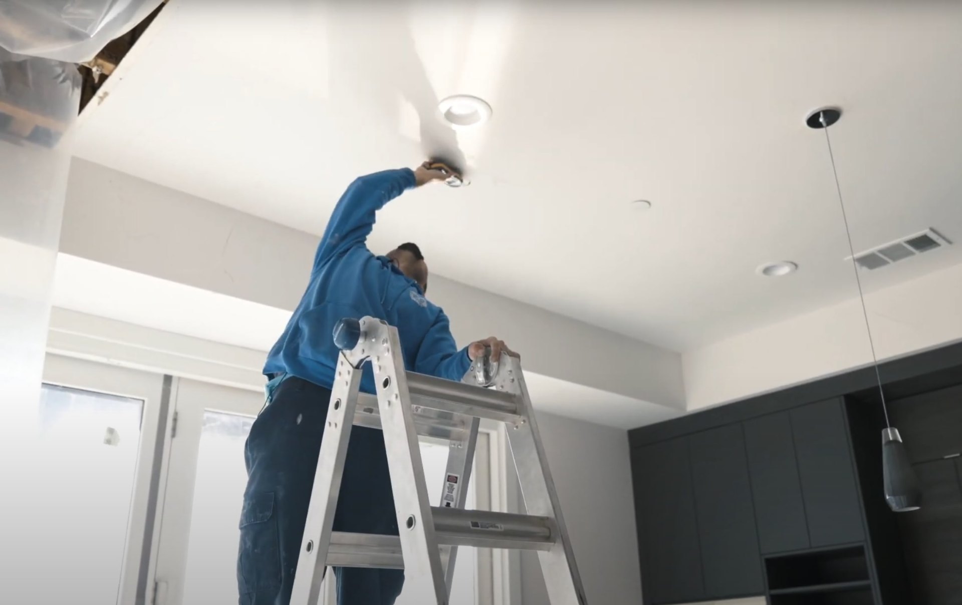 Water damage restoration specialist performing ceiling repairs with professional equipment