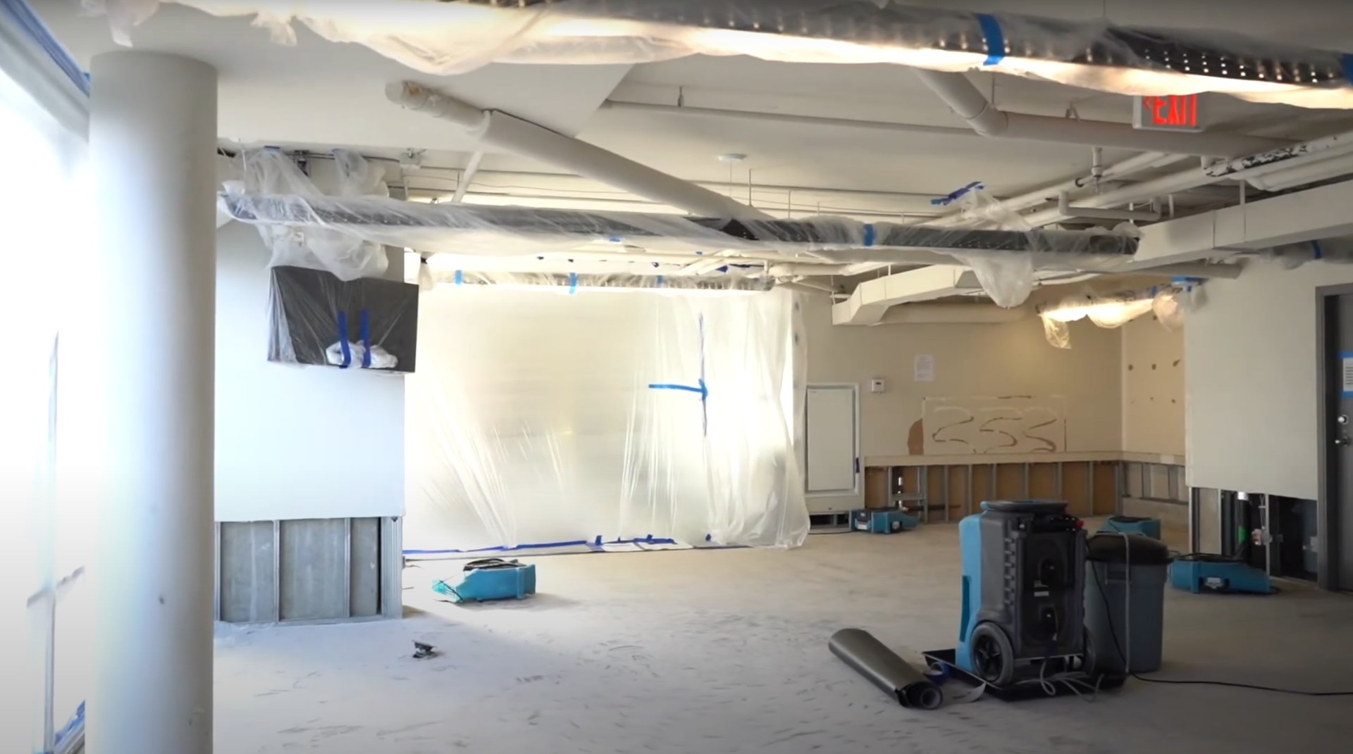 Commercial water damage restoration in progress with professional drying equipment and plastic sheeting